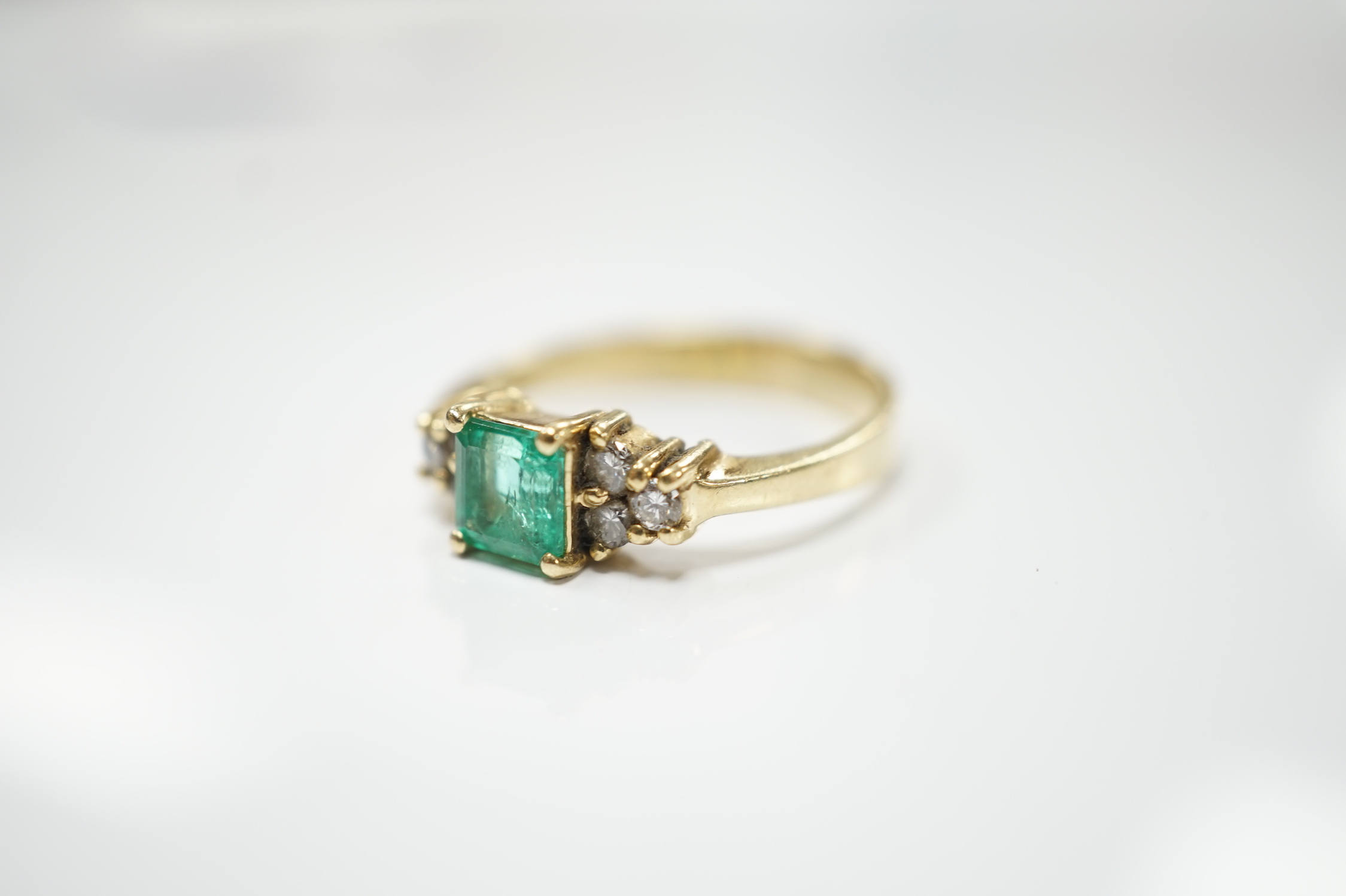 A modern 18k, emerald and diamond set cluster ring, size N, gross weight 3.8 grams.